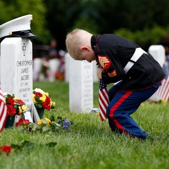 Christian Jacobs, 5, of Hertford, N.C., dressed as a Marine, works to place a flag in front of his father's gravestone on Memorial Day in Section 60 at Arlington National Cemetery in Arlington, Va., Monday, May 30, 2016. Christian's father Marine Sgt. Christopher James Jacobs died in a training accident in 2011. (AP Photo/Carolyn Kaster)